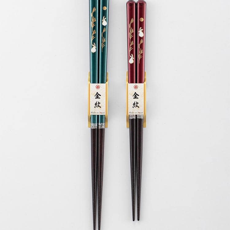 Red and green lacquered chopsticks showcasing intricate motifs.