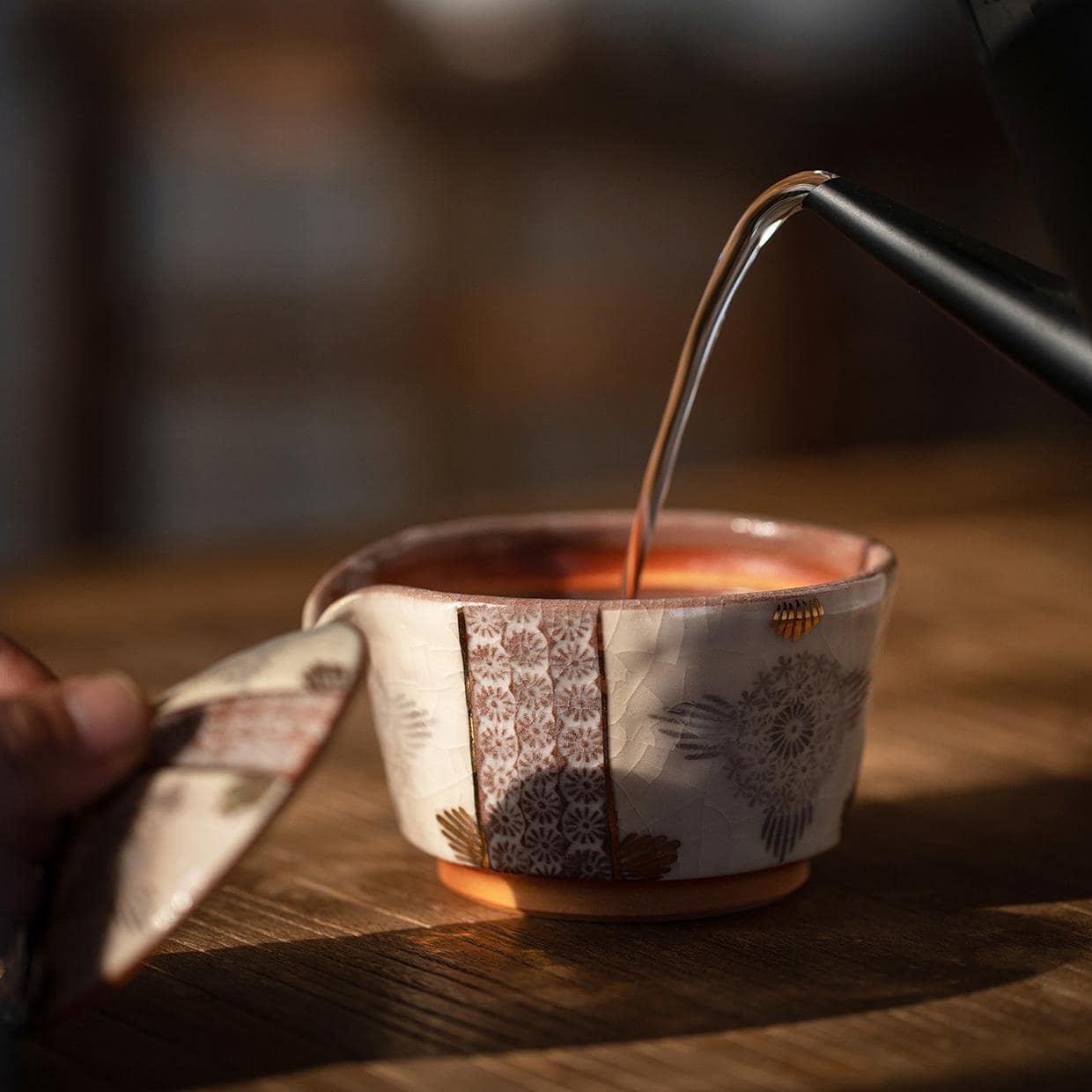 Handcrafted Japanese Kiyomizu-yaki teapot and cup on a wooden tray.