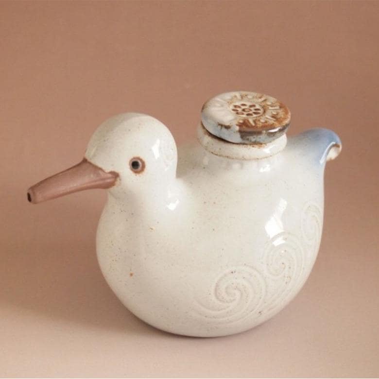 Close-up of zakka-style bird seasoning bottle on a kitchen table.