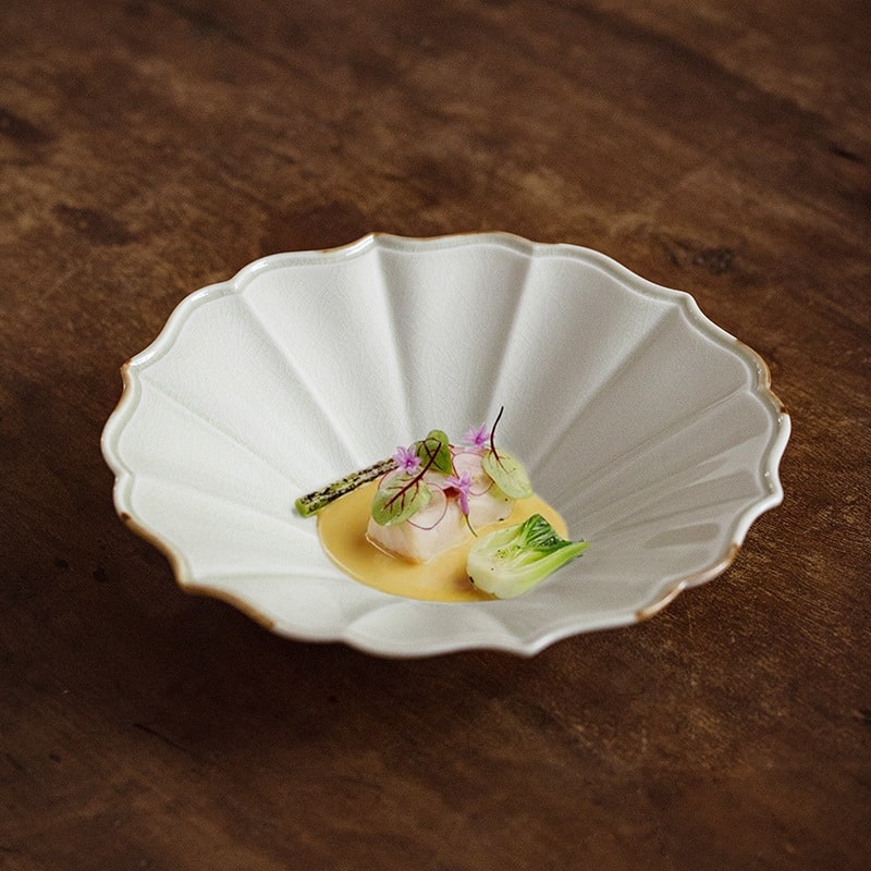 Ivory ceramic plate with scalloped edges and golden accents.