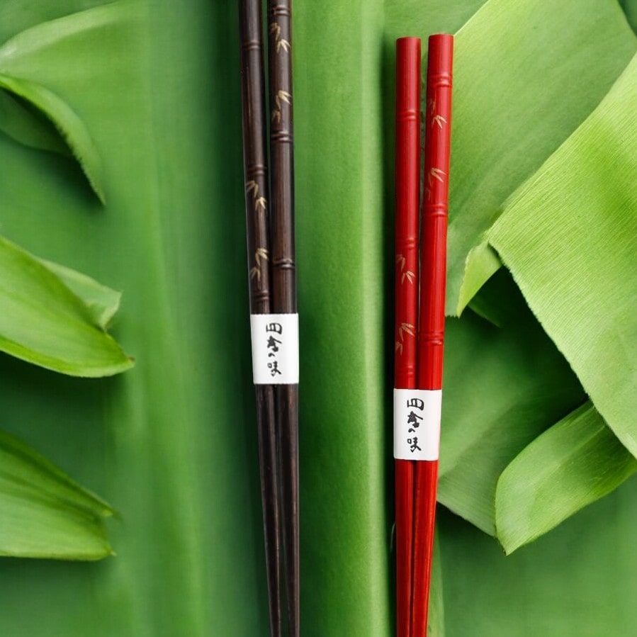 Pair of red lacquer-coated chopsticks with engraved bamboo design.