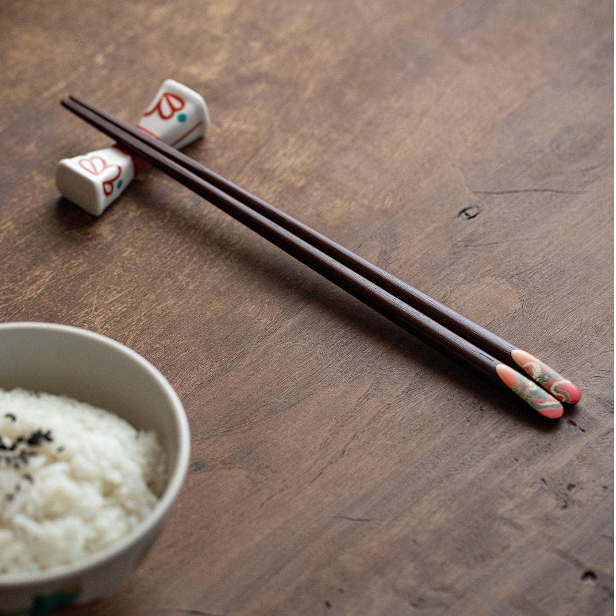 Close-up of hand holding chopsticks with intricate dragon design