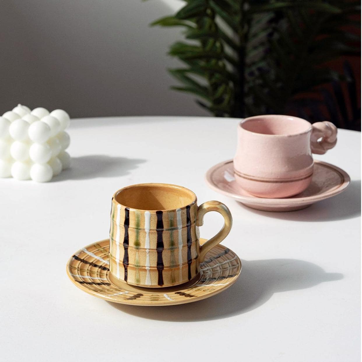 Vibrant yellow striped ceramic mug and saucer on a wooden table.