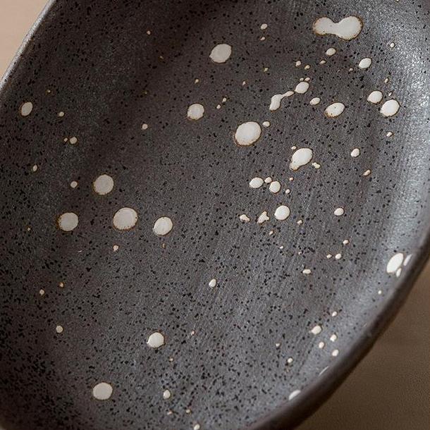 Rustic ceramic plate with splattered black design on table