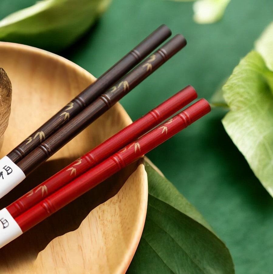 Japanese chopstick set featuring red and brown finishes on a green background.