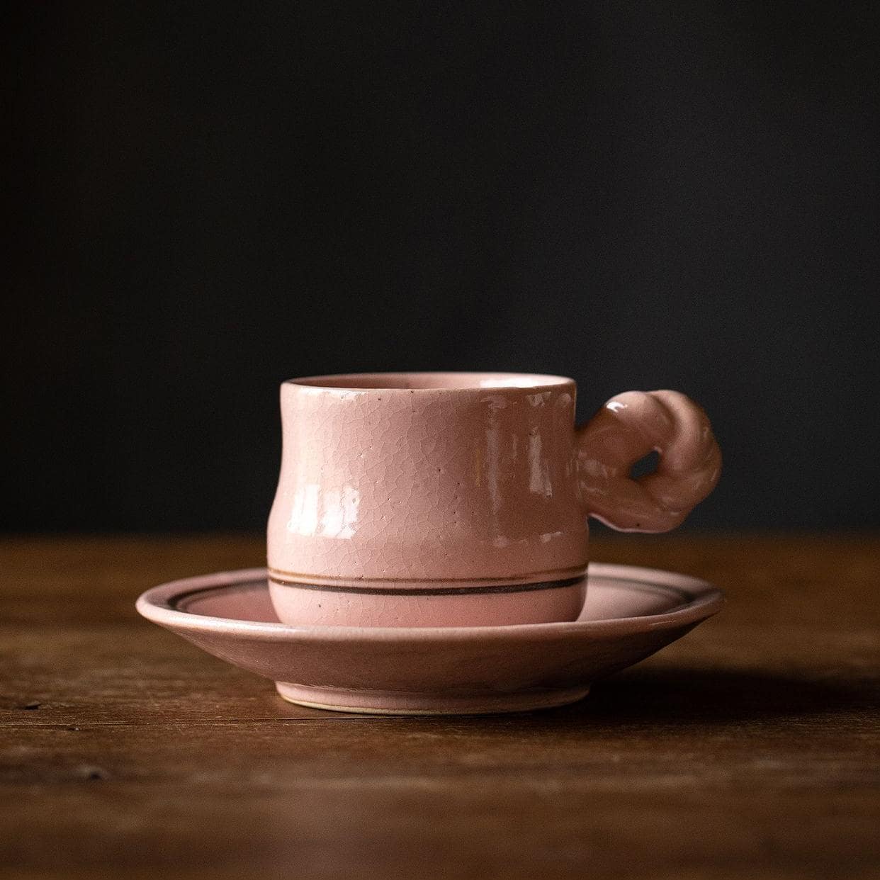 Close-up of handmade ceramic tea mug with unique pink handle.