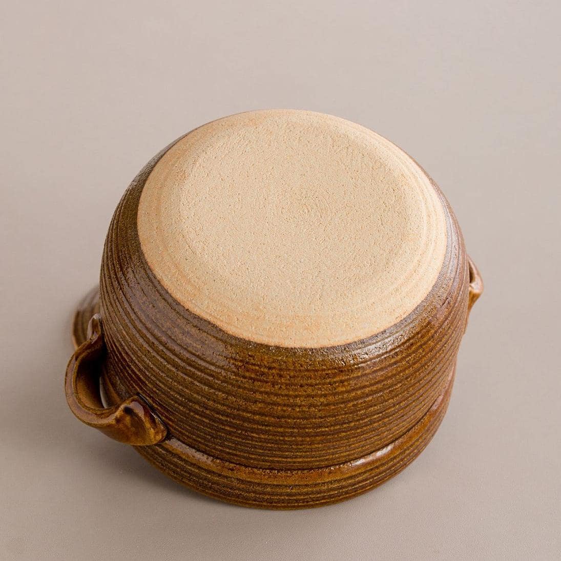 Hand lifting the lid of a black Japanese Shinraku-yaki cooking pot