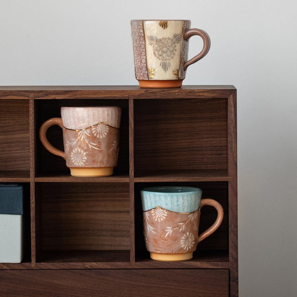 Handcrafted ceramic mugs with floral patterns and gold accents on display