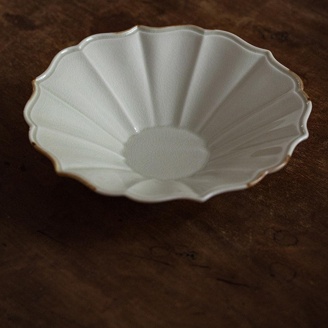 Handcrafted scalloped ceramic plate on a wooden table.