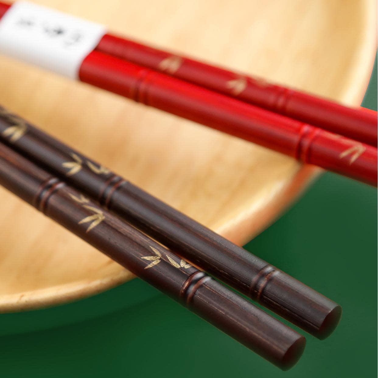 Pair of red lacquer-coated chopsticks with engraved bamboo design.