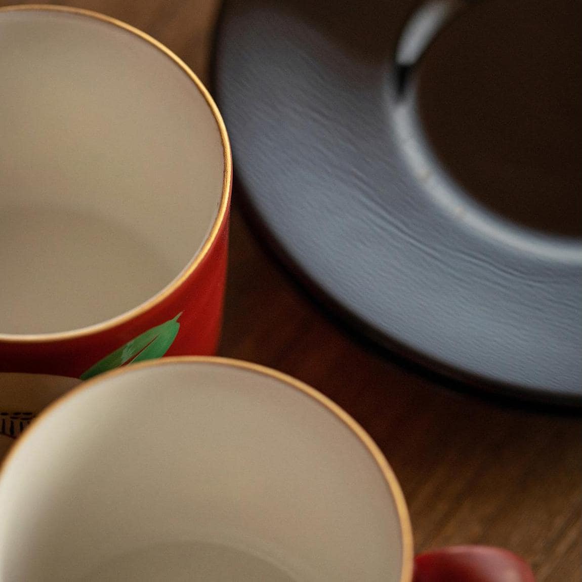 Close-up of red painted couple cups on black saucers.