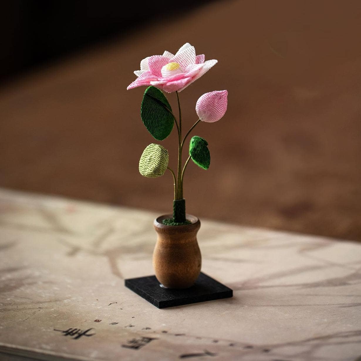 Close-up of delicate fabric flowers on wooden base