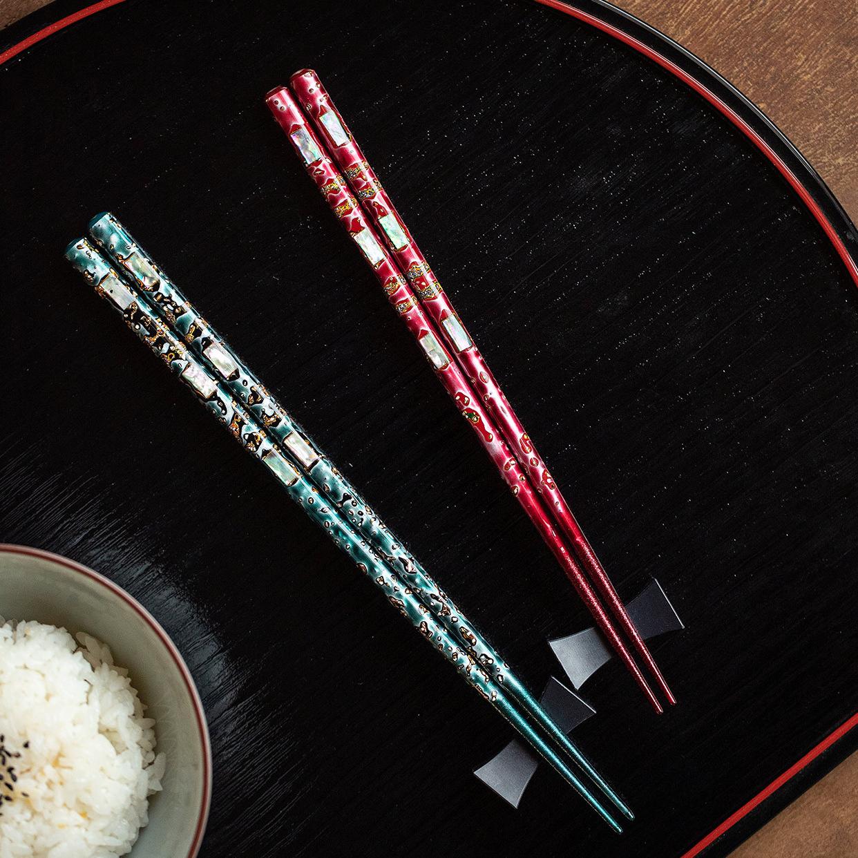 Japanese Wakasa wooden chopsticks with vibrant lacquer finish on a white plate.