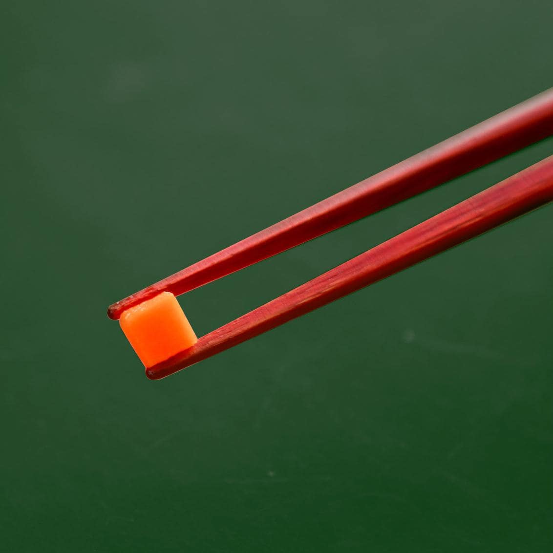 Japanese chopstick set featuring red and brown finishes on a green background.