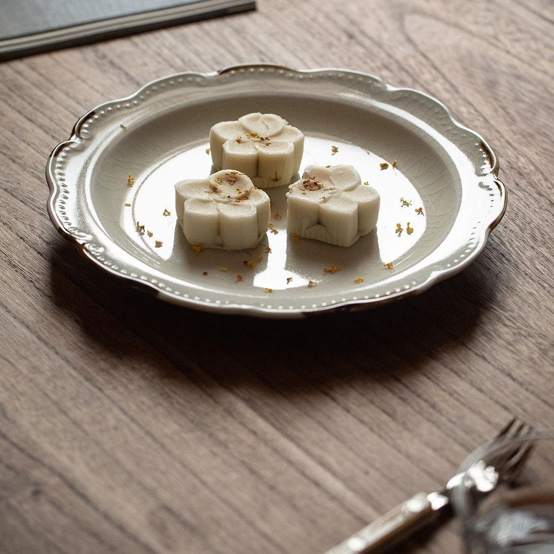 Ivory ceramic plate with scalloped edges and golden accents.