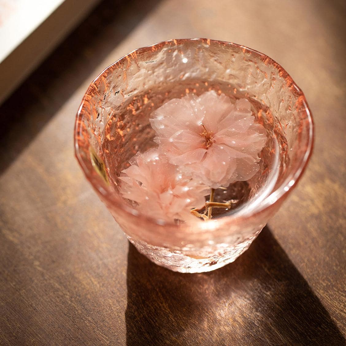 Cherry blossom-inspired pink glass cup with textured finish.