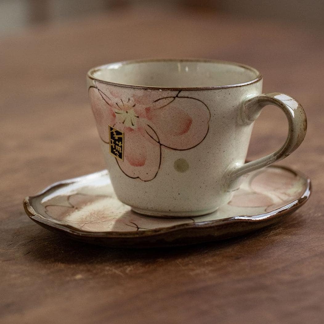 Close-up of sakura-themed ceramic tea cup and matching saucer.