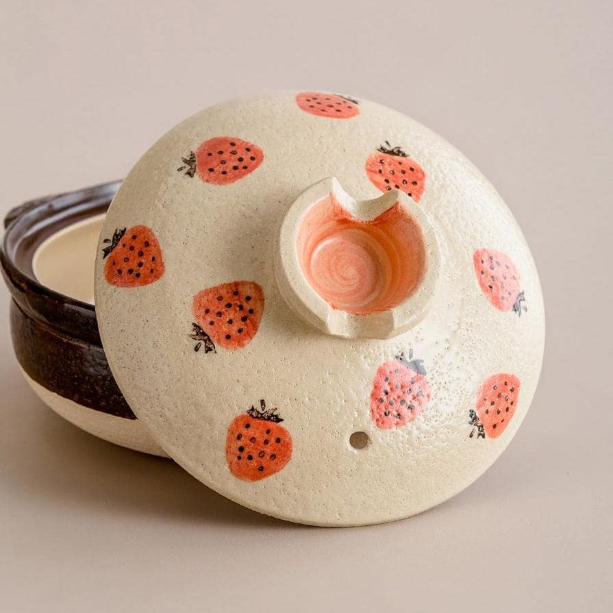 Close-up of a ceramic pot with a playful strawberry motif.