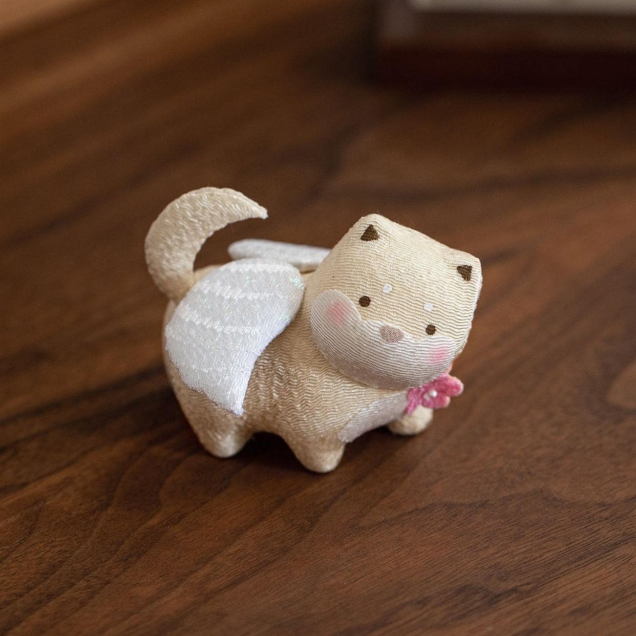 Pastel ceramic lucky cat figurines on a wooden shelf