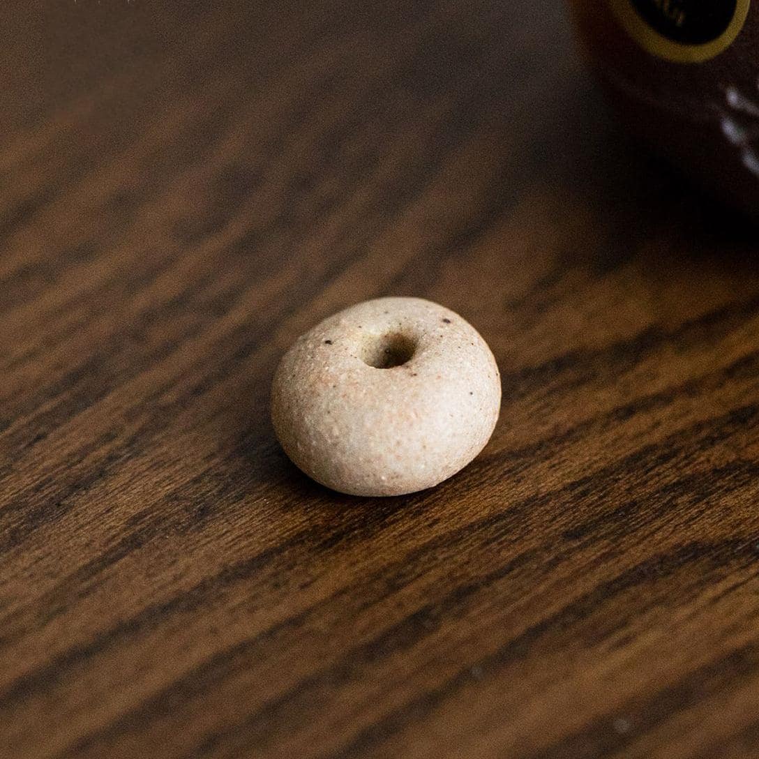 Close-up of Shinraku pottery cat incense holder on a brown tray.