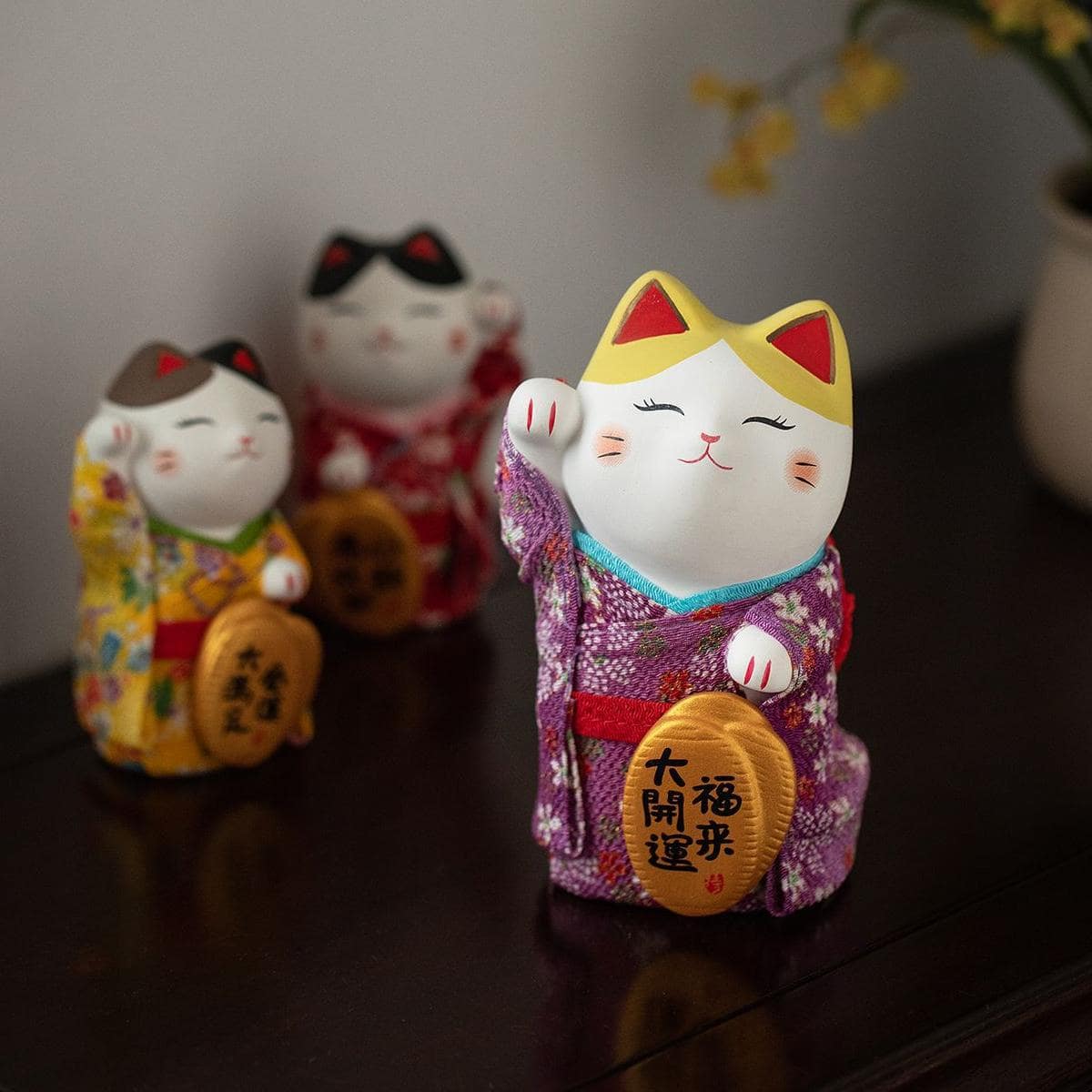 Collection of colorful Maneki Neko ceramic ornaments in traditional kimonos.