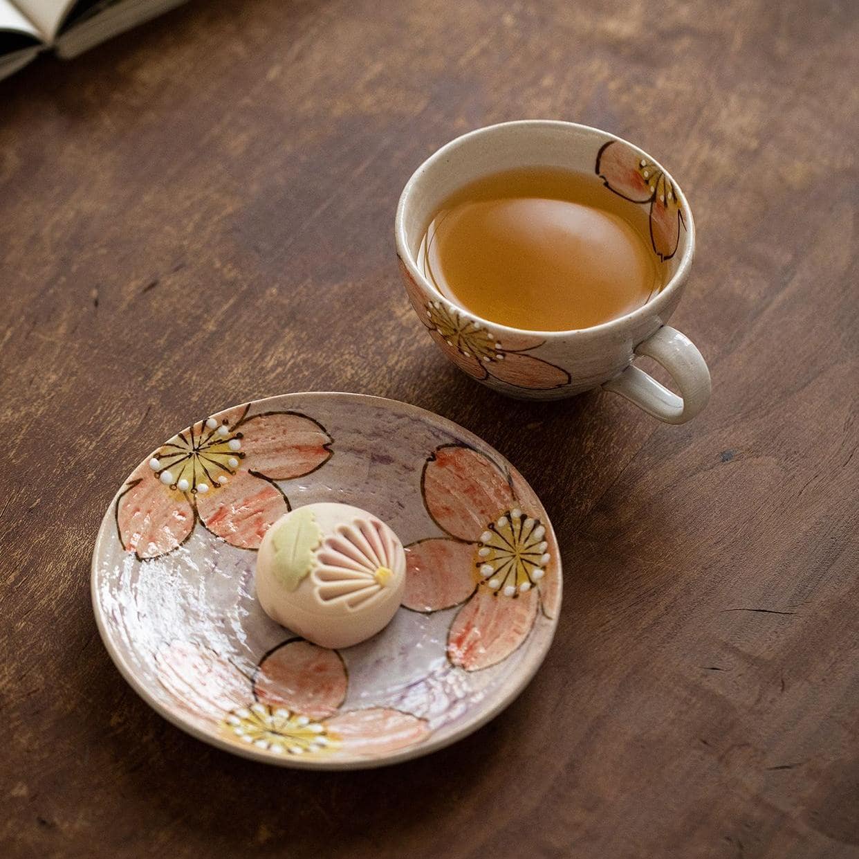 Spring-inspired sakura tea cup and saucer on a wooden table.