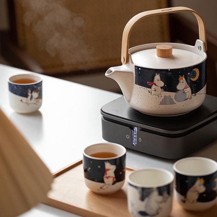 Pastel pink Moomin ceramic tea set with whimsical designs.