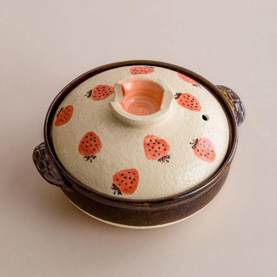 Artisan ceramic donabe pot with whimsical strawberry details.