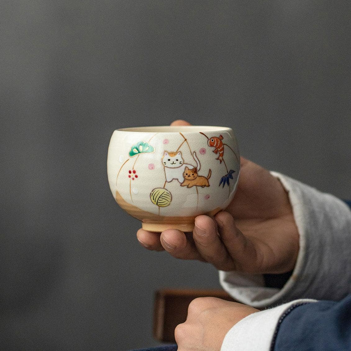 Collection of hand-painted ceramic cups with whimsical designs on a wooden shelf.