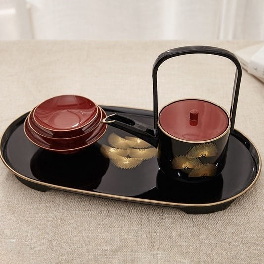 Black lacquered tea cup set with golden floral accents and tray.