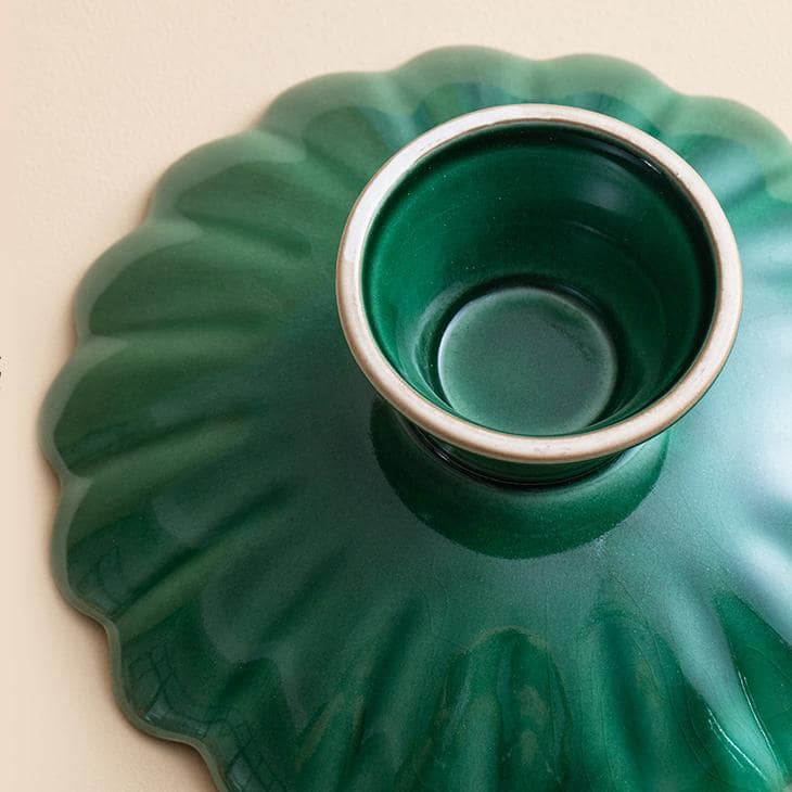 Elevated green ceramic plate with pedestal design for serving desserts.