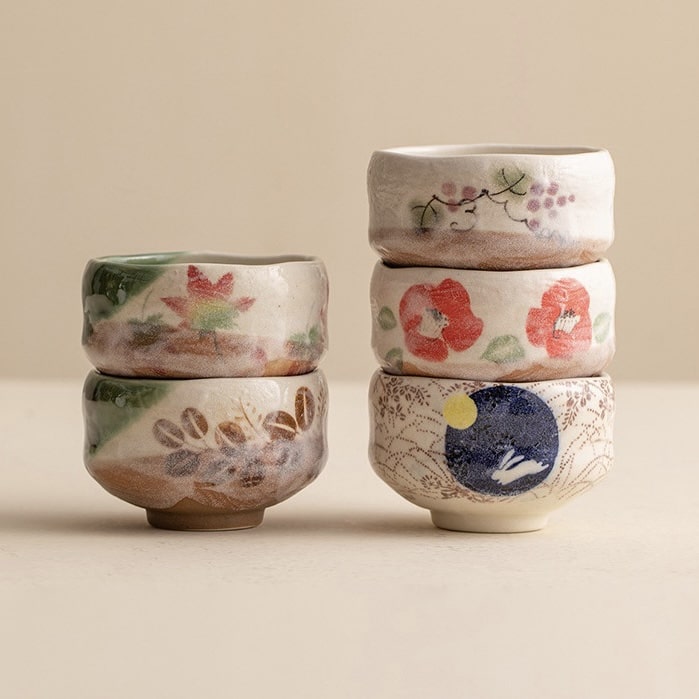 Close-up of tea cups featuring delicate floral and nature-inspired designs.