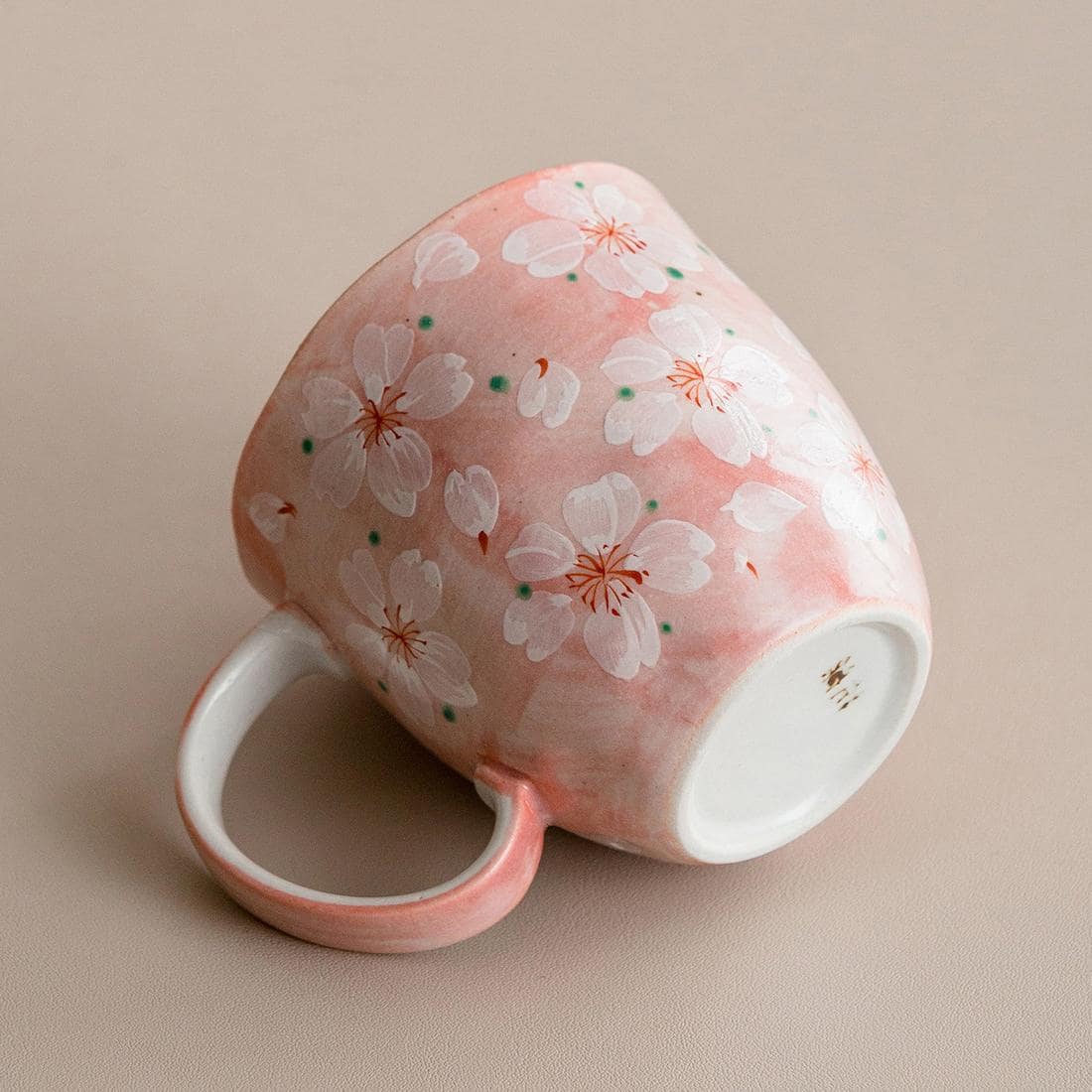 Blue hand-painted cherry blossom coffee cup on a wooden table.