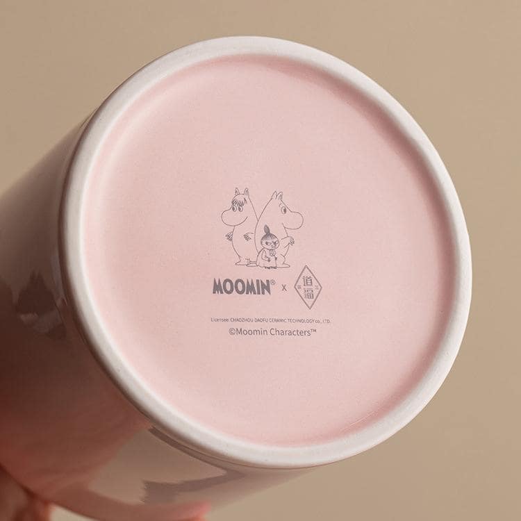 Pastel pink Moomin ceramic tea set with whimsical designs.