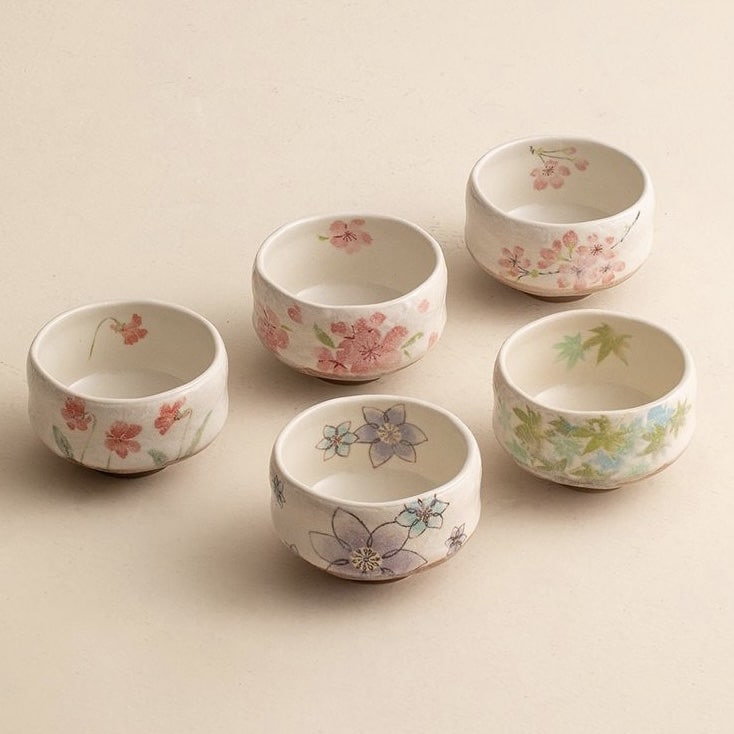 Artisanal tea set with intricate hand-painted details on each cup.