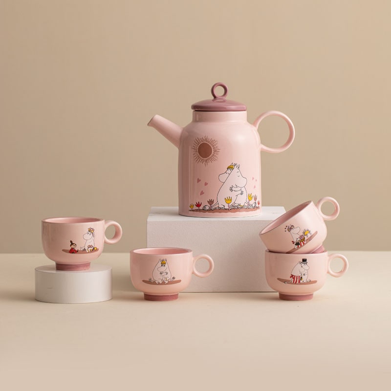 Pastel pink Moomin ceramic tea set with whimsical designs.