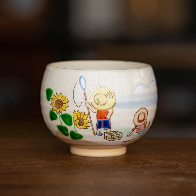 Close-up of a ceramic cup featuring vibrant sunflowers and summer scenes.