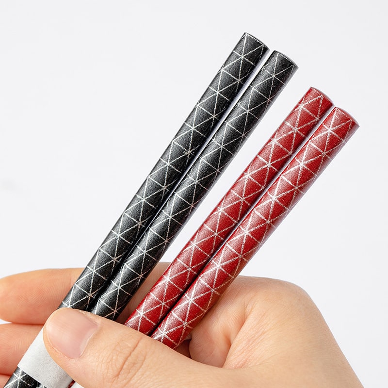 Close-up of textured non-slip star-point chopsticks in red and black.