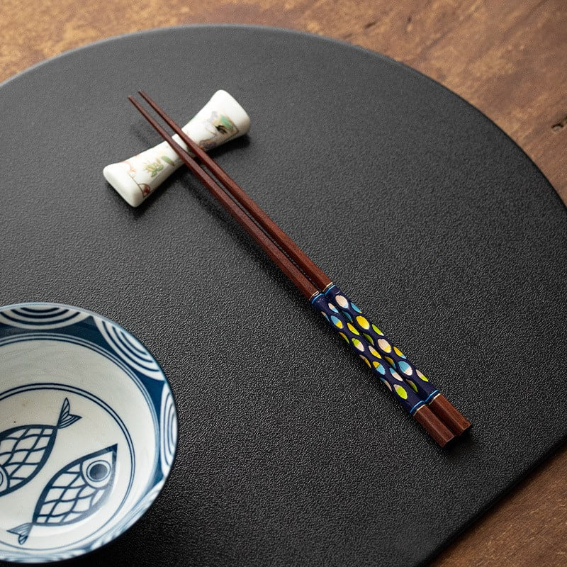 Stylish wooden chopsticks placed on a dining plate with vibrant patterns.