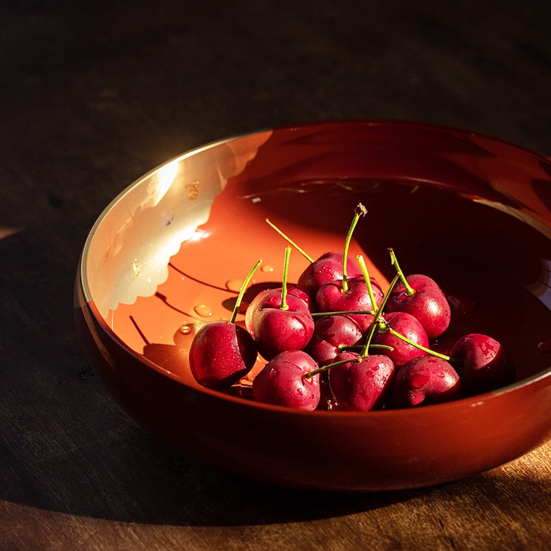 Elegant red and gold lacquer fruit plate with cherries.