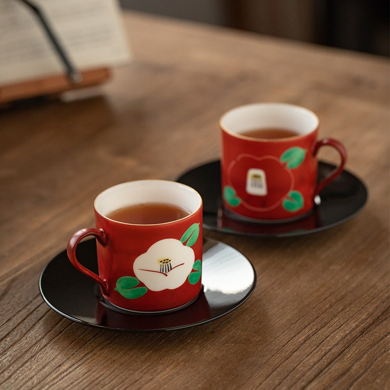Close-up of red painted couple cups on black saucers.