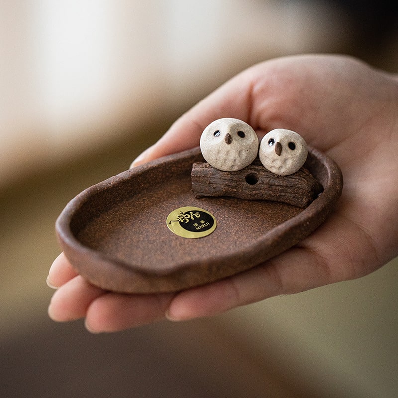 Close-up of Shinraku pottery cat incense holder on a brown tray.