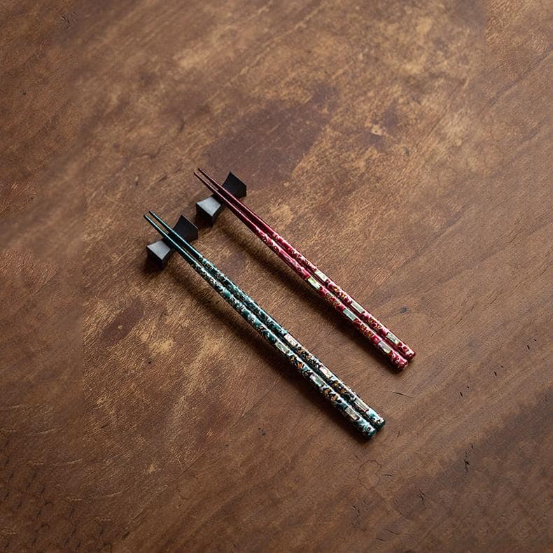 Elegant Japanese chopsticks displayed with sushi on a wooden table.