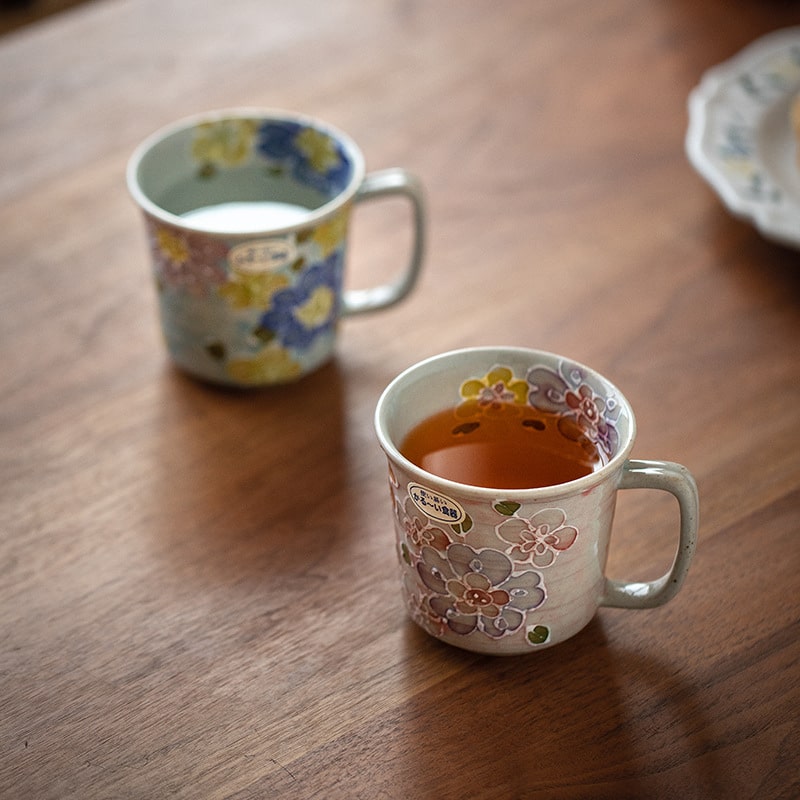 Two ceramic mugs with floral patterns on a wooden surface