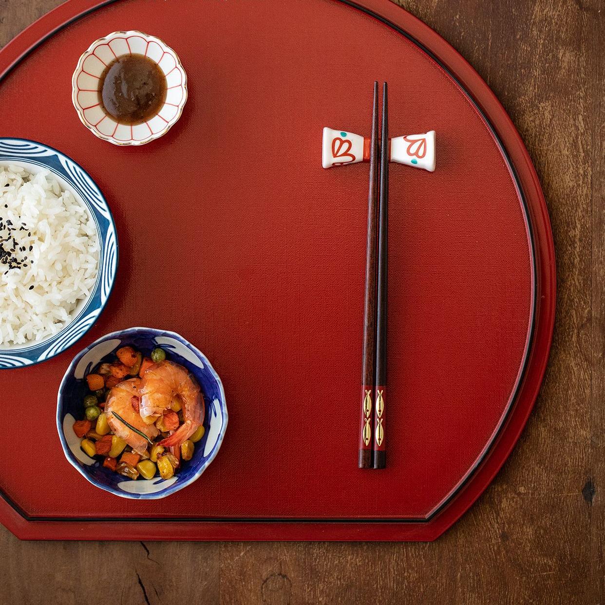 Elegant red and black chopstick set resting on ceramic plate