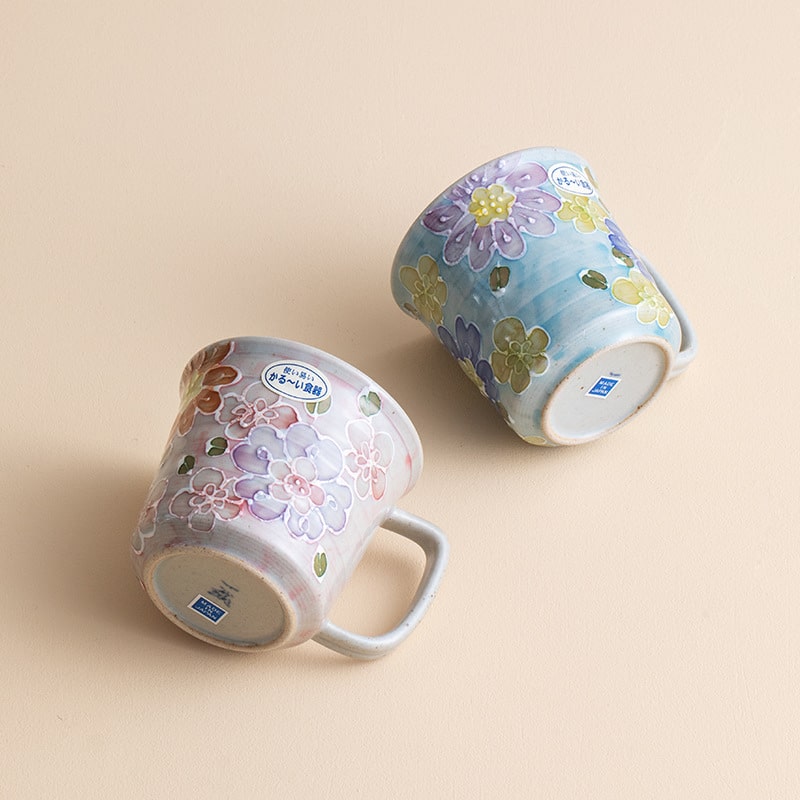 Pair of floral ceramic mugs displayed on a beige background