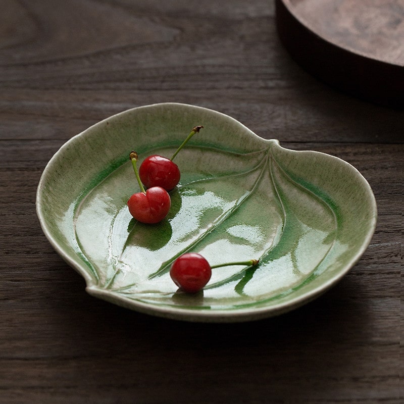 Handcrafted ceramic plate resembling a natural leaf on a wooden table