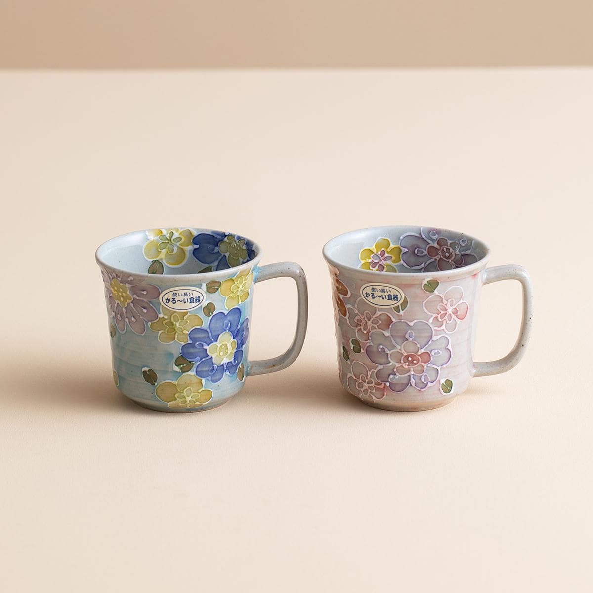 Hand holding a floral ceramic mug with vibrant colors