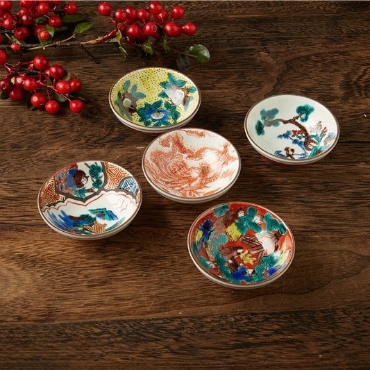 Close-up of ceramic tea cups featuring traditional Japanese art.
