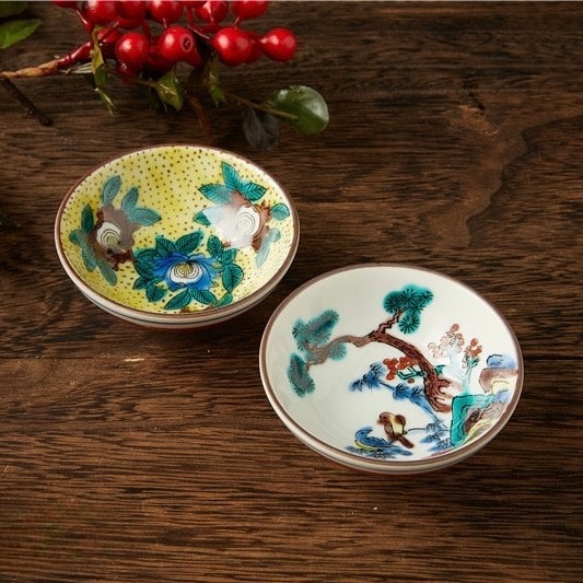 Close-up of ceramic tea cups featuring traditional Japanese art.
